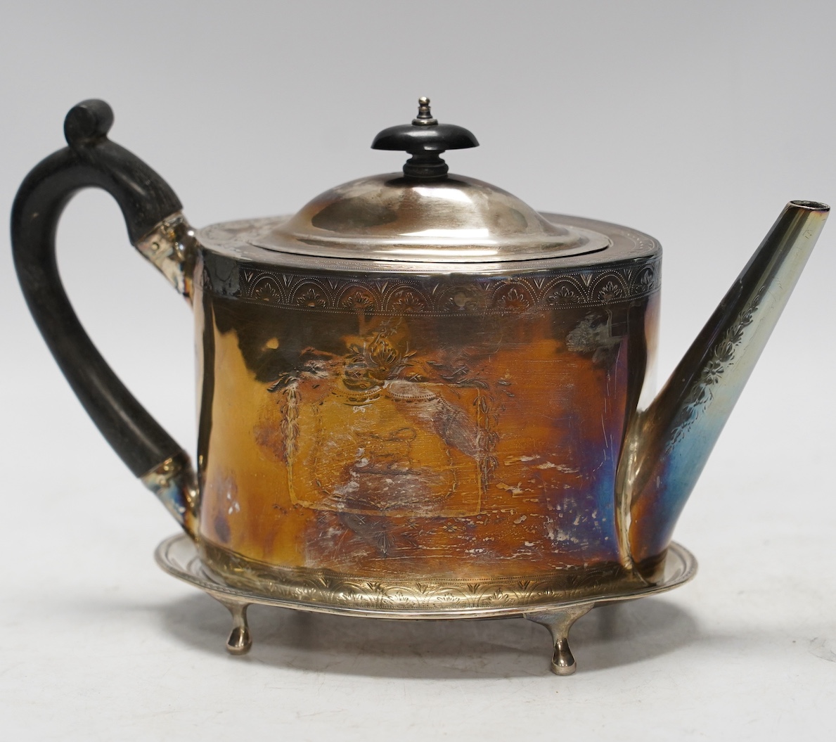 A George III engraved silver oval teapot, Cornelius Bland, London, 1791(poor condition), together with an associated oval stand (fair condition), Soloman Hougham, London, 1797, 16.2cm, gross 16oz.